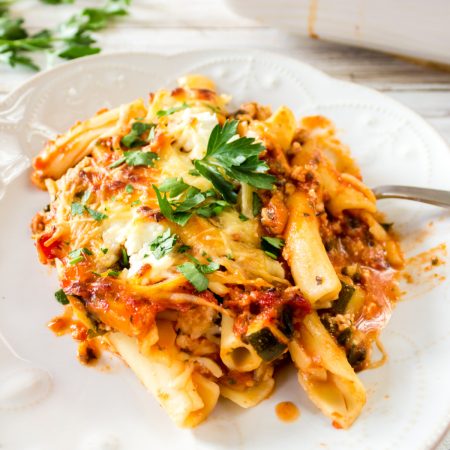 A plate of baked ziti topped with melted cheese and fresh parsley.