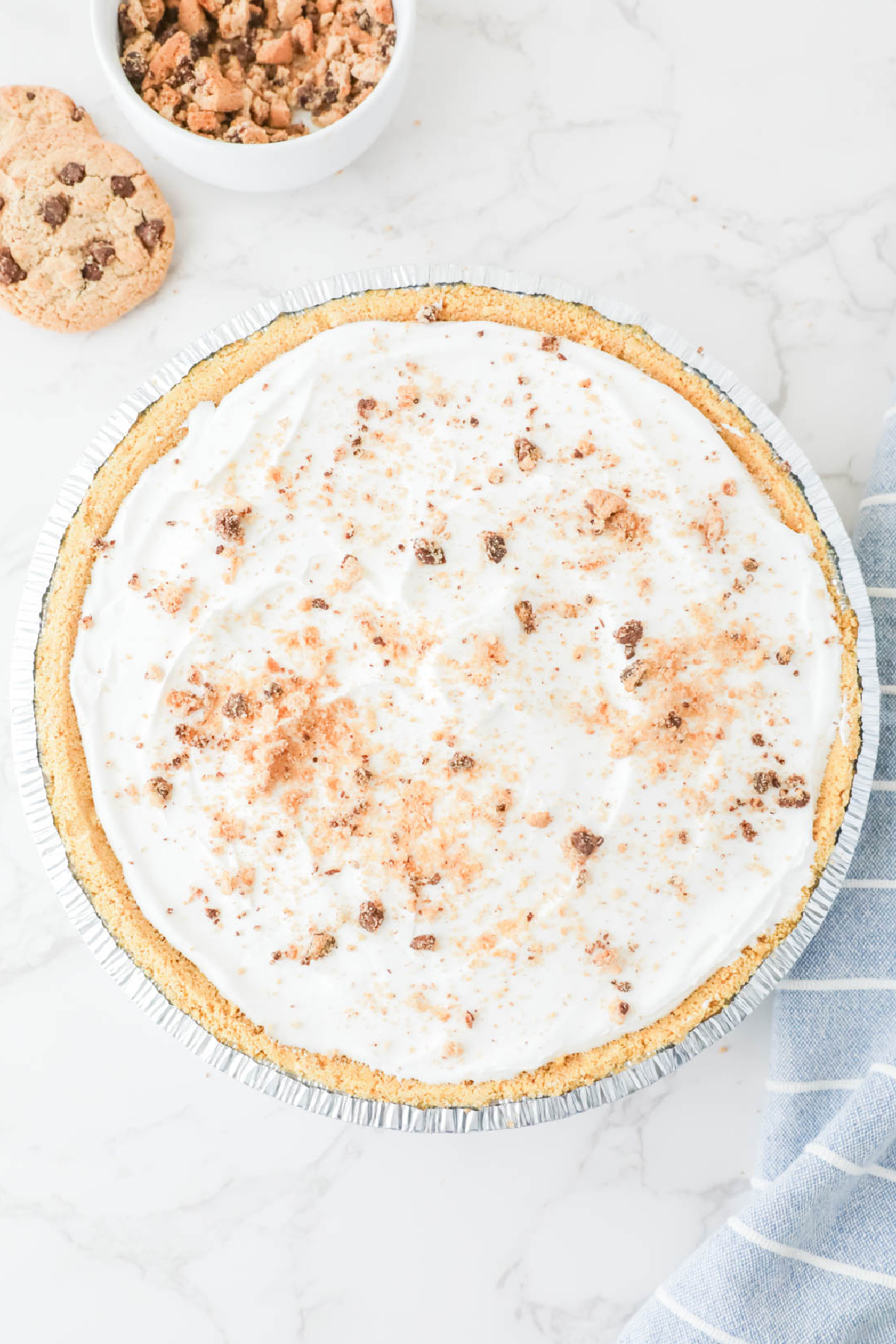 A freshly made cookie cream pie on a marble countertop, garnished with cookie crumbs.