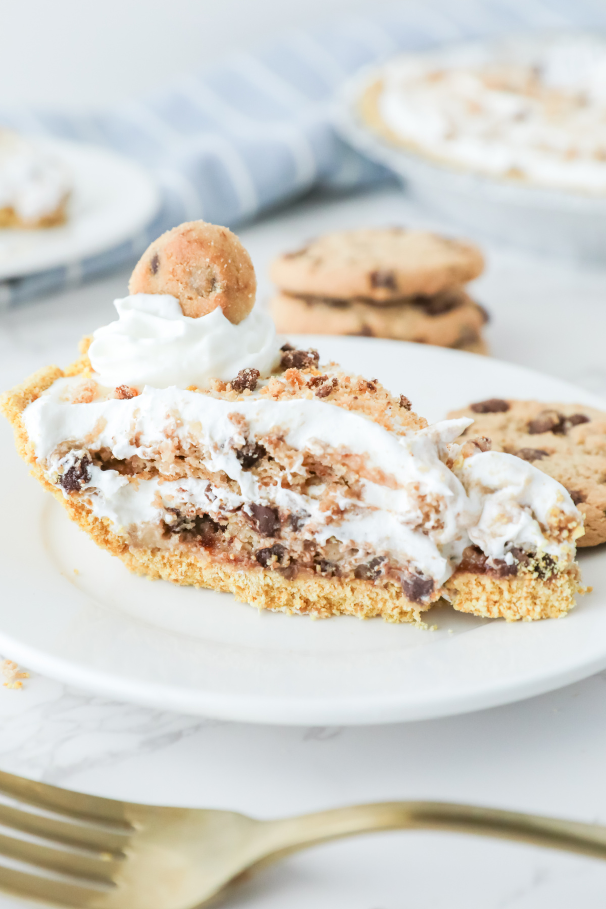 A slice of Cool Whip cookie pie topped with whipped cream on a white plate with whole cookies in the background.