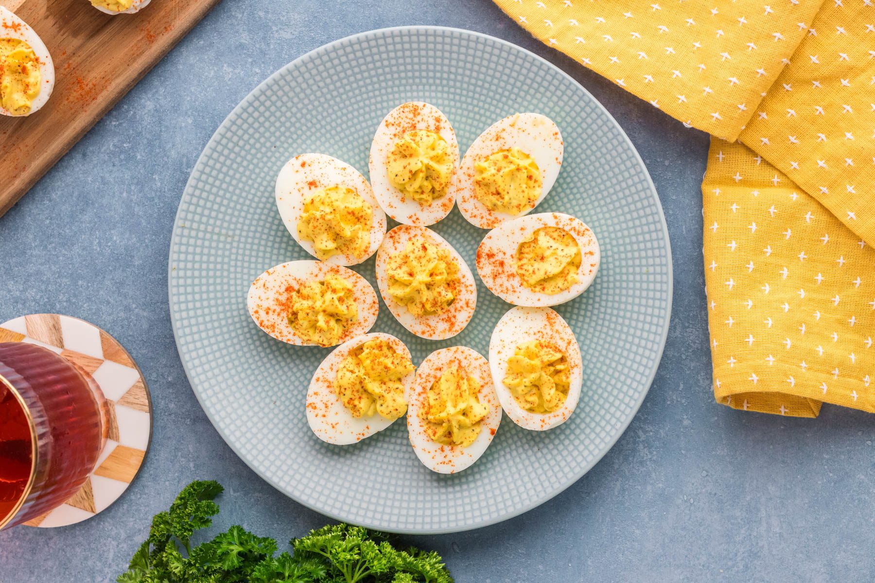 Plate of deviled eggs garnished with paprika on a blue plate.