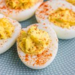 Deviled eggs sprinkled with paprika on a blue patterned plate.