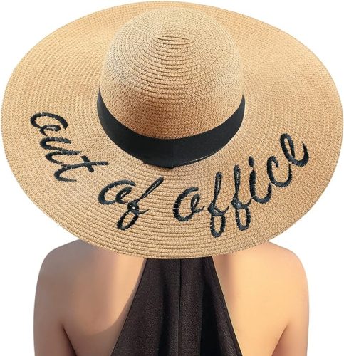 A person wearing a wide-brimmed straw hat with the words "out of office" embroidered on it.