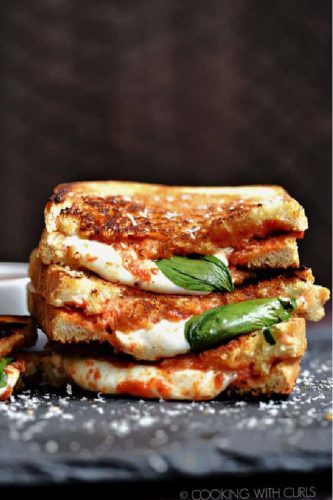 Grilled cheese sandwich with tomato and basil on a dark background.