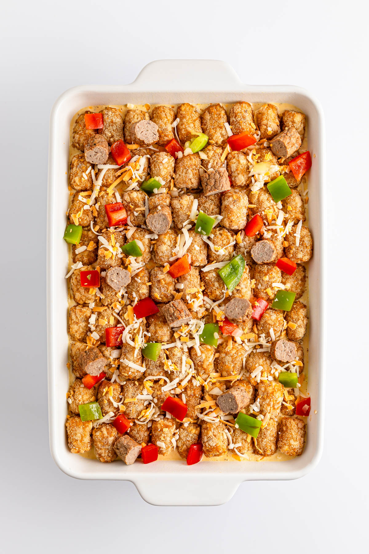 A casserole dish filled with seasoned tofu, bell peppers, and shredded cheese.