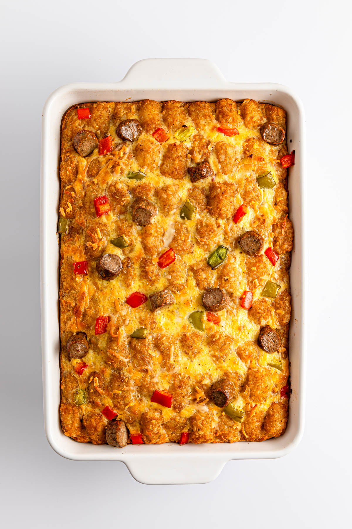 Baked casserole with sausage and vegetables in a white dish.