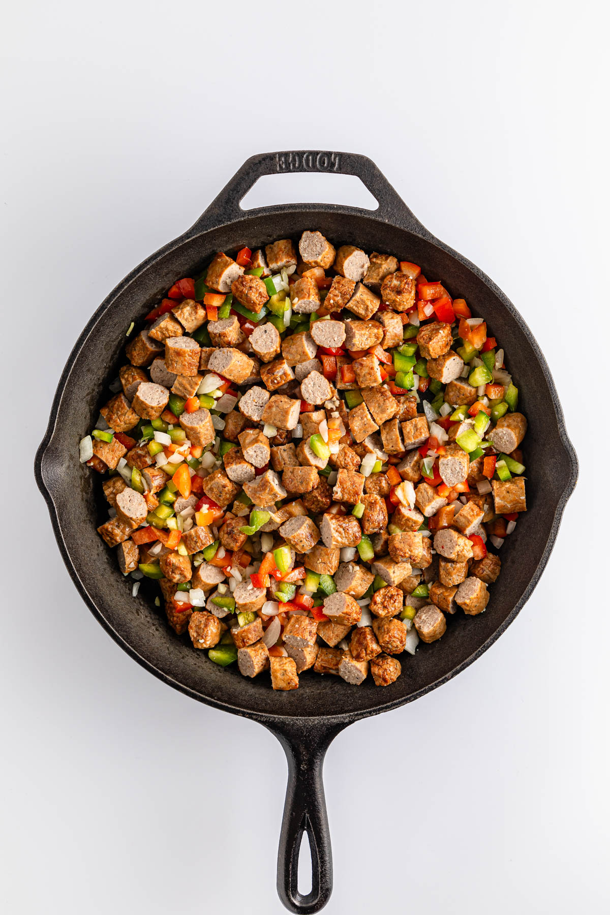 Diced vegetables and tofu cooking in a cast-iron skillet.