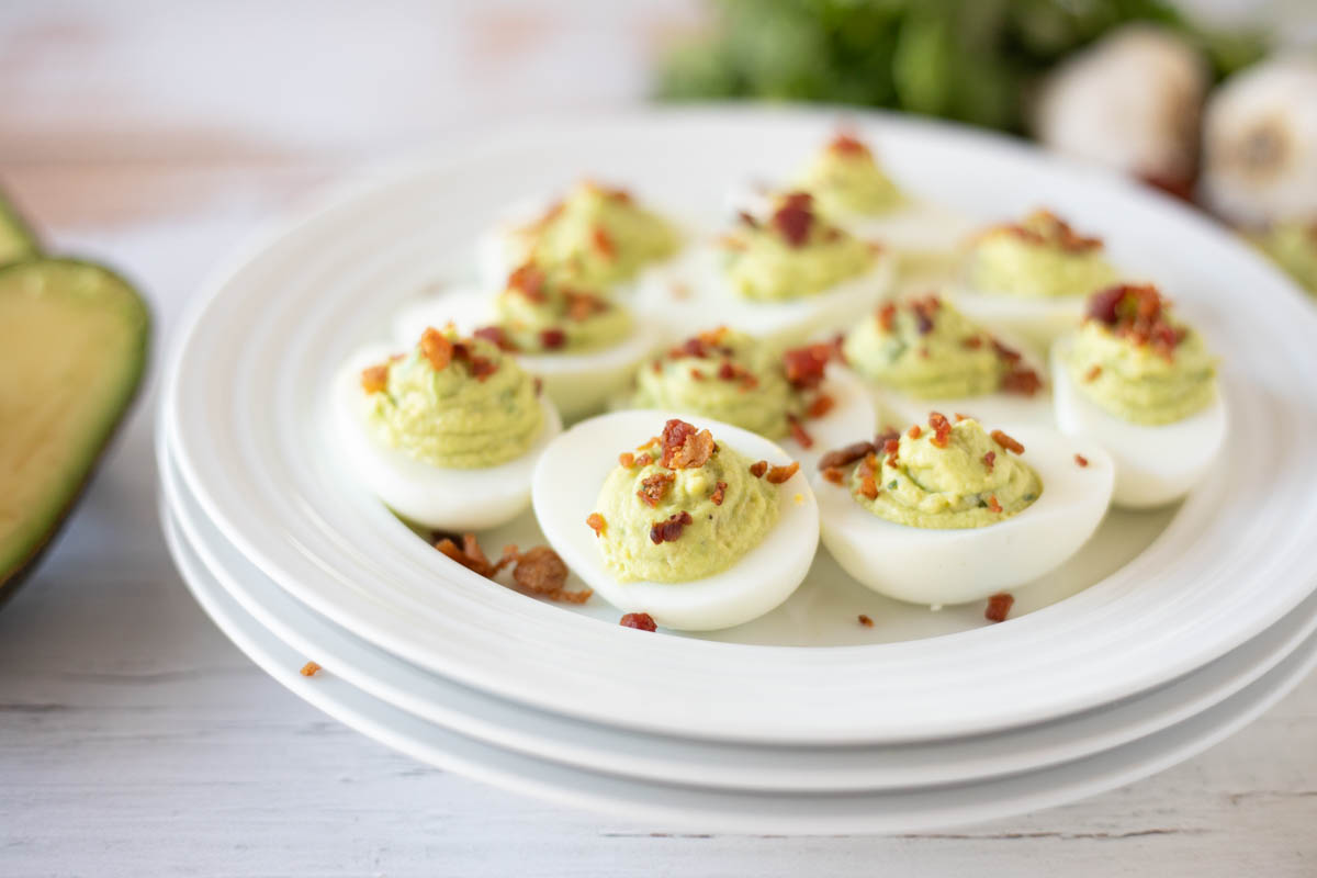 A plate of deviled eggs topped with bacon crumbles and spices.