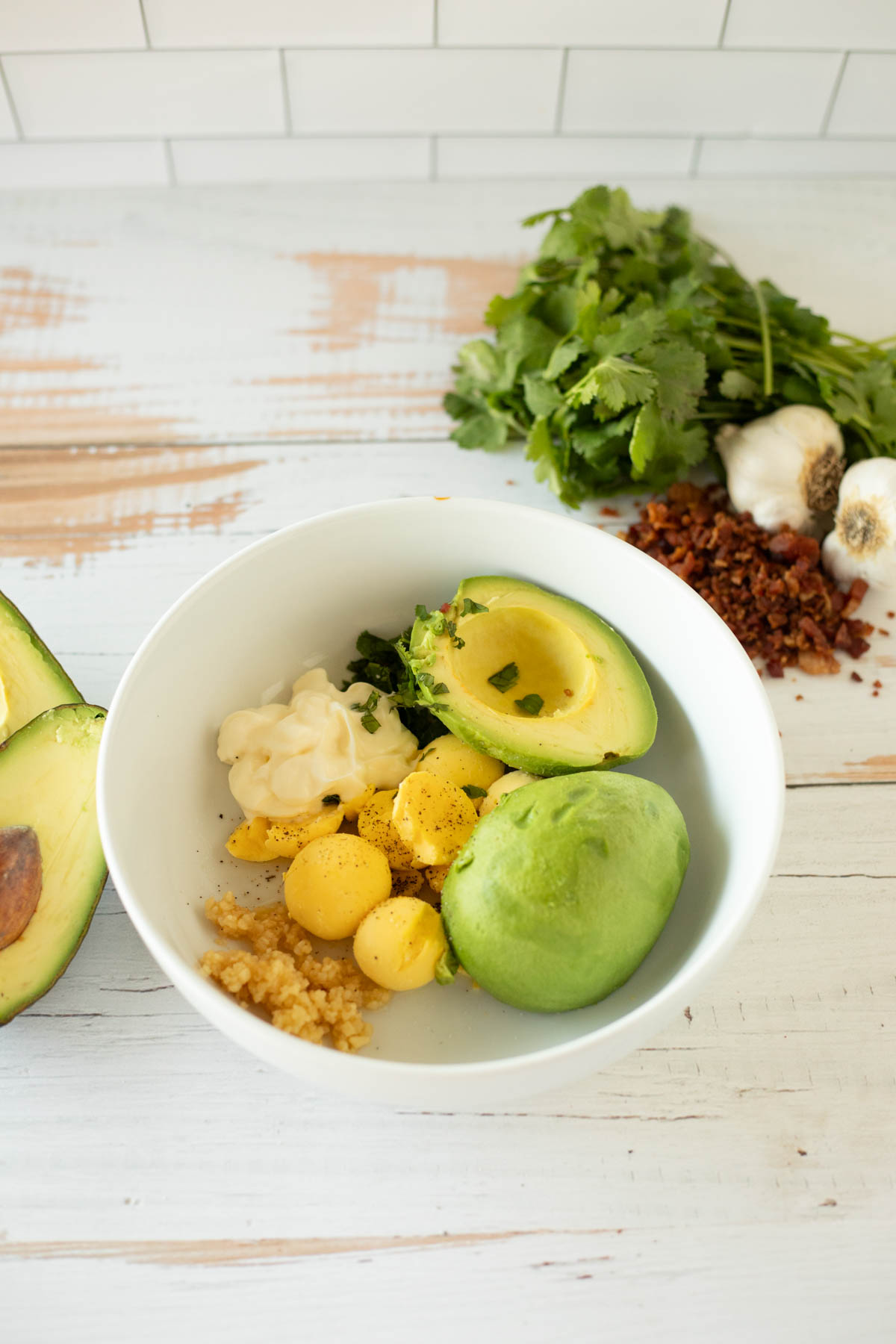 Ingredients for avocado deviled eggs in white bowl