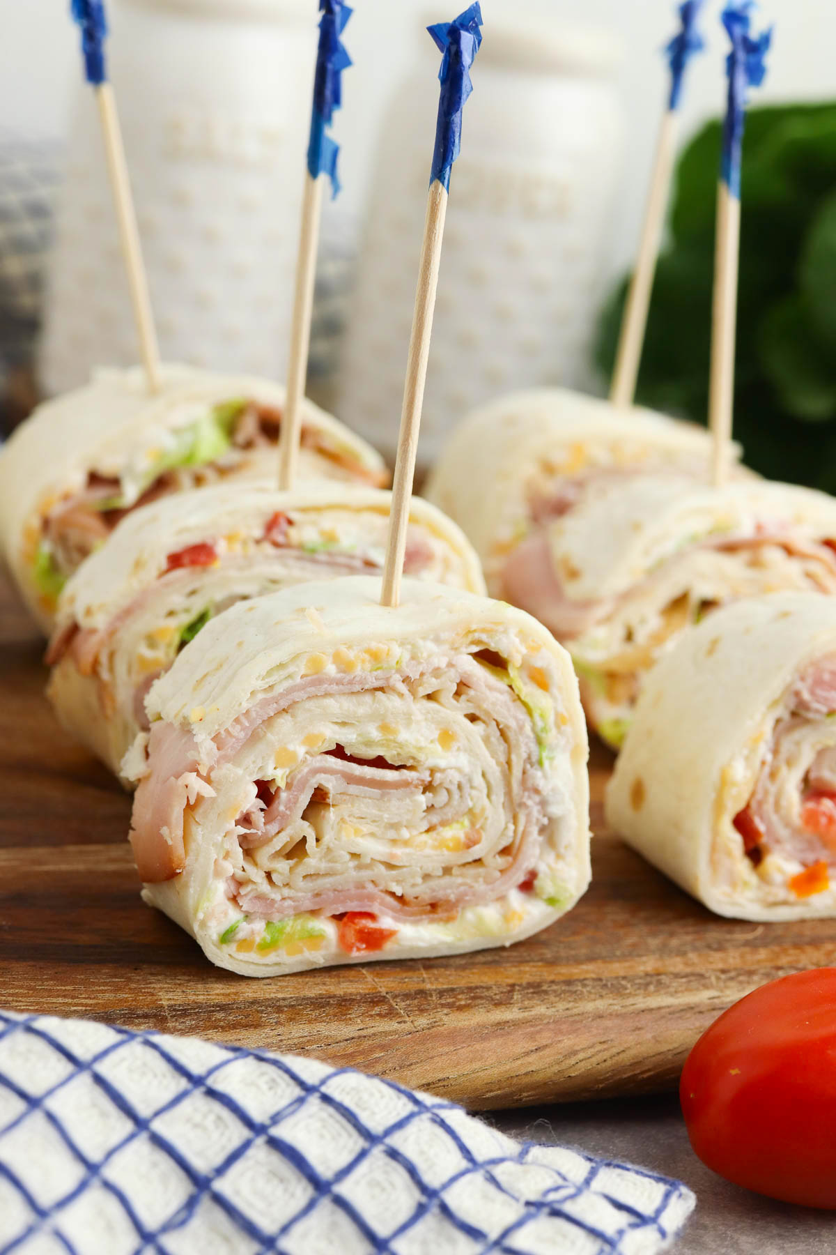 Sliced turkey and cheese wrap pinwheels secured with toothpicks on a wooden board.