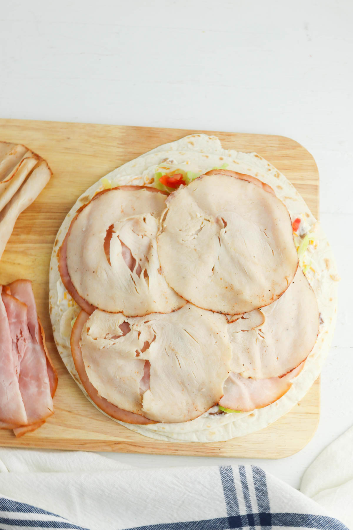 Turkey slices layered on an open tortilla wrap on a wooden cutting board.