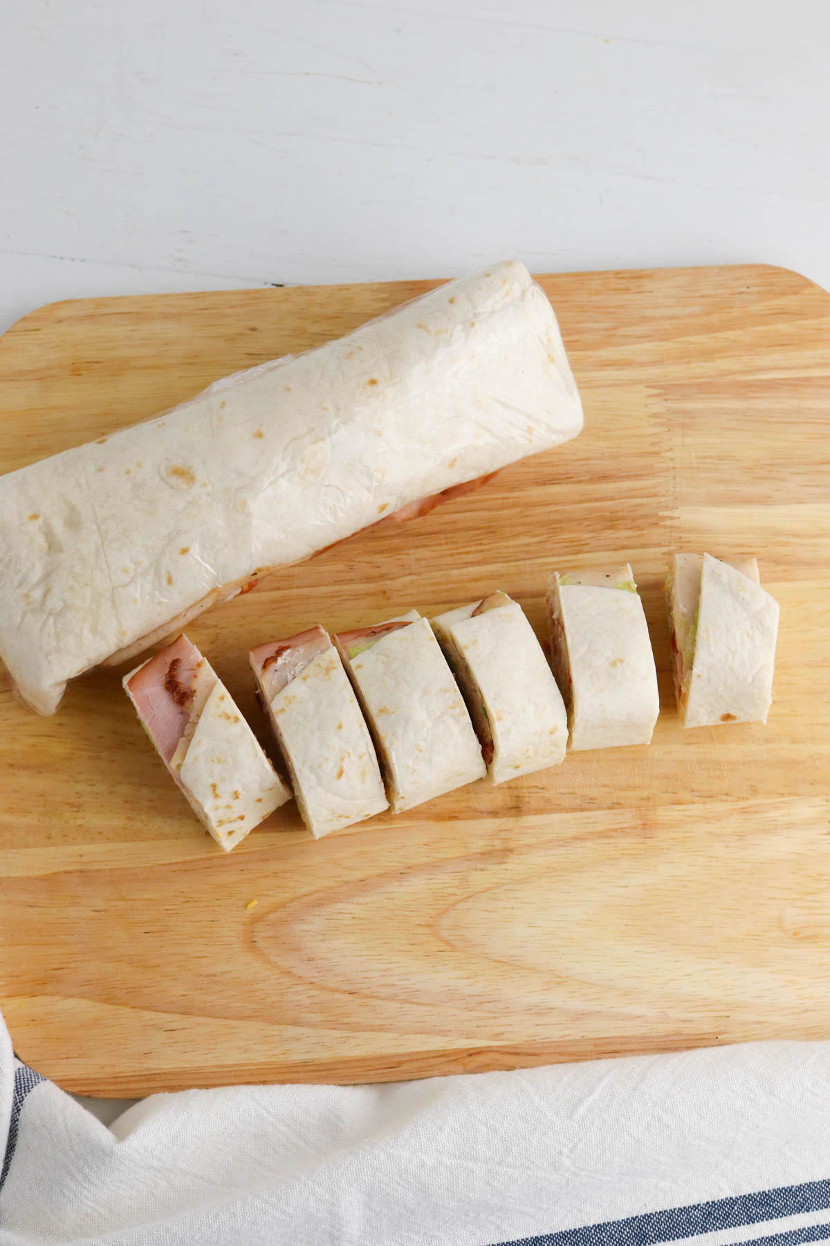 A sliced wrap sandwich on a wooden cutting board.