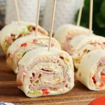 Sliced turkey and cheese pinwheel sandwiches on wooden skewers.