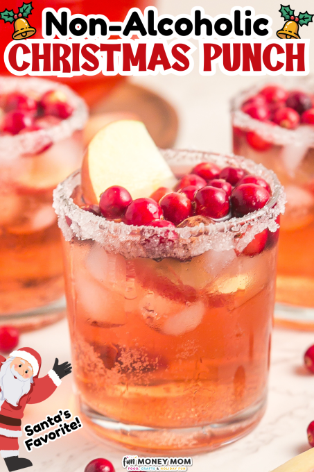 A glass of non-alcoholic Christmas punch with ice, cranberries, and an apple slice, rimmed with sugar, surrounded by similar drinks.