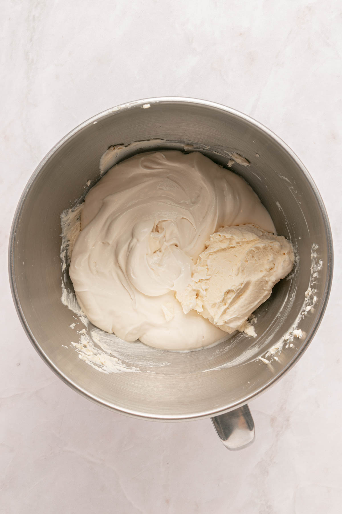 A mixing bowl containing a thick, smooth, tiramisu cream on a light-colored surface.