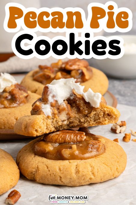Close-up of pecan pie cookies, one broken in half with whipped cream on top, displayed on a light surface with pecan pieces scattered around.