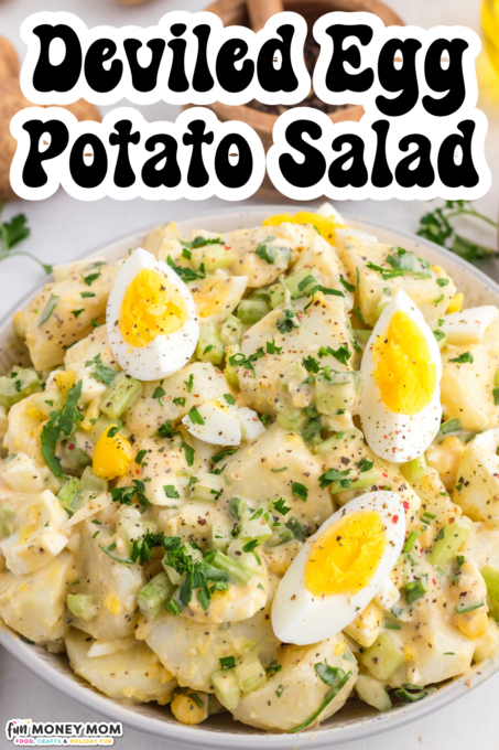 A bowl of deviled egg potato salad garnished with sliced hard-boiled eggs, chopped parsley, and black pepper.