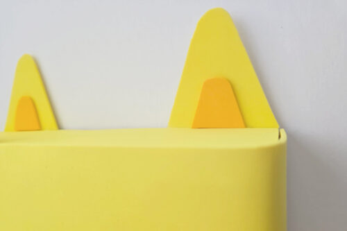 Yellow triangle ears for an owl craft against a plain white background