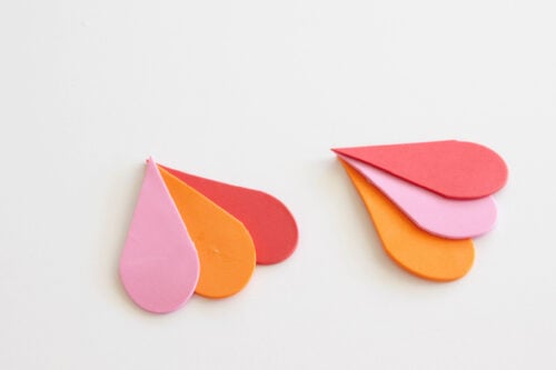 Two sets of colorful teardrop-shaped paper cutouts, each set arranged in a fan shape on a white background.
