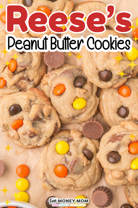 A batch of peanut butter cookies topped with Reese's Pieces and mini peanut butter cups, displayed on a light surface.