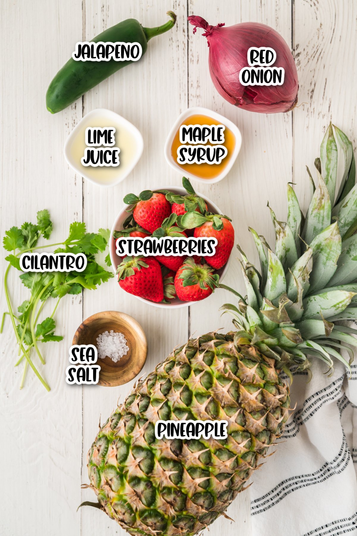 A bowl of strawberries and a pineapple.