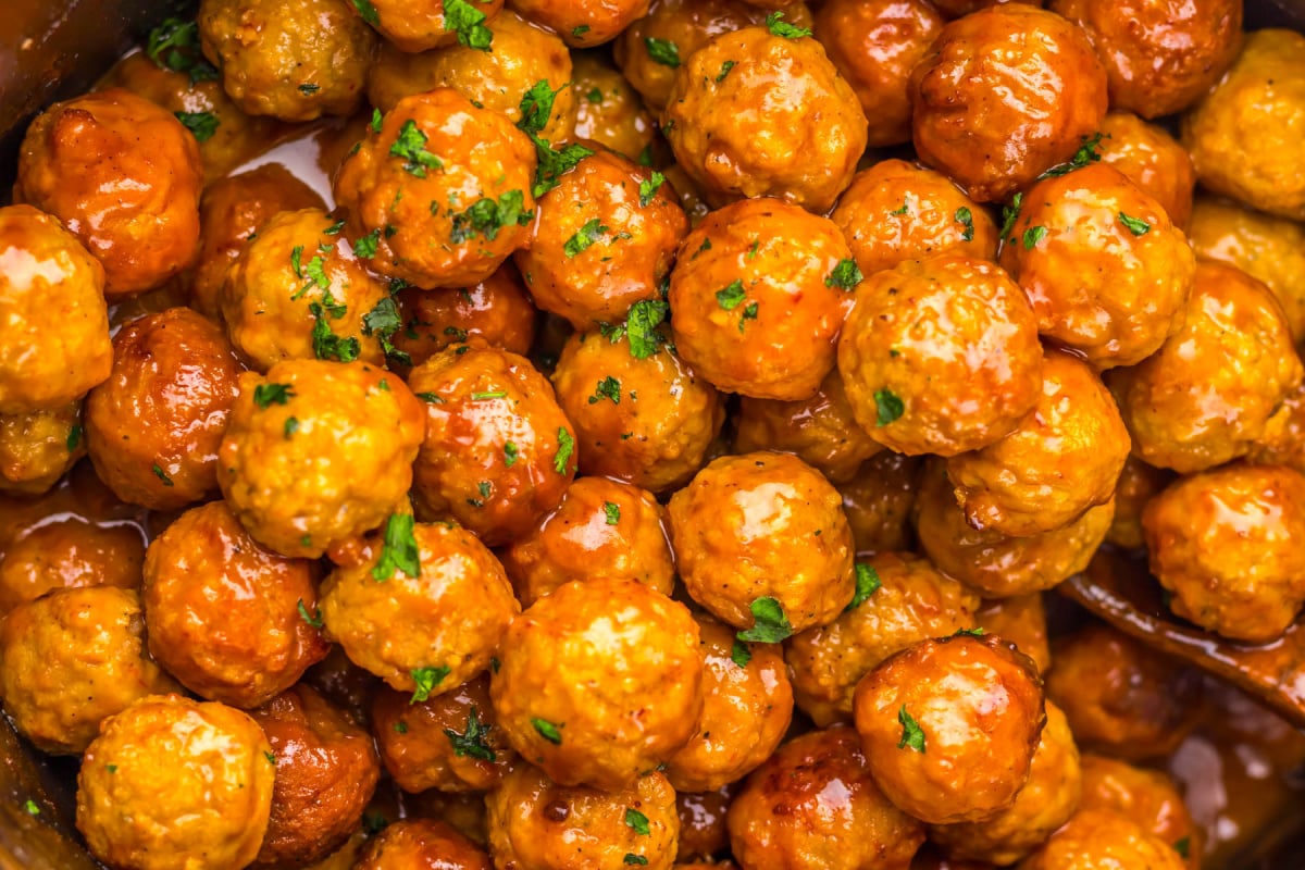 Close-up of sauced meatballs garnished with chopped parsley.