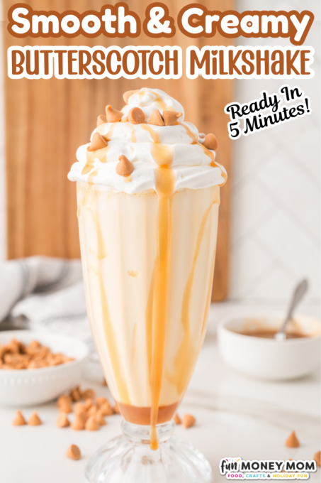 A tall glass of butterscotch milkshake topped with whipped cream and butterscotch chips, with caramel drizzle and a straw. Bowls of butterscotch chips are in the background.