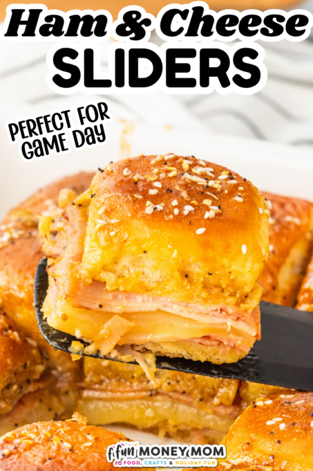 A spatula lifts a ham and cheese slider with a golden, sesame-topped bun from a dish of sliders. Text reads “Ham & Cheese Sliders” and “Perfect for Game Day.”.