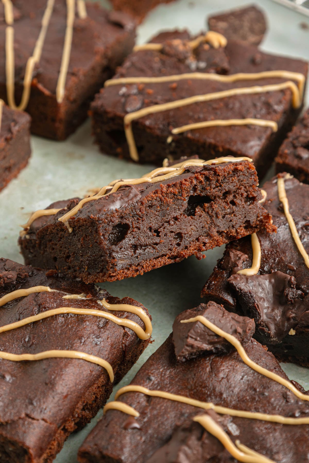 Several sweet potato brownies, some cut in half, are arranged on a tray and drizzled with a light-colored icing.