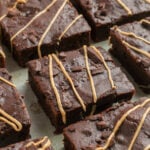 Close-up of several sweet potato brownies topped with light-colored drizzle, arranged in rows on a flat surface.