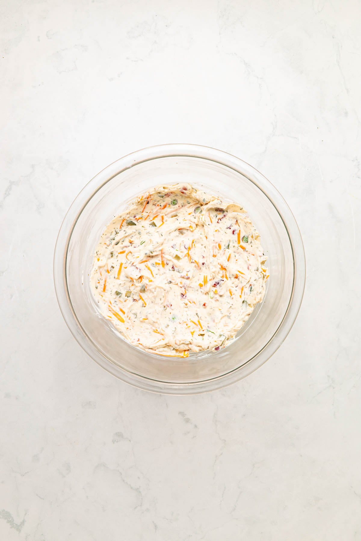 Glass bowl filled with a creamy mixture, placed on a white marble surface.