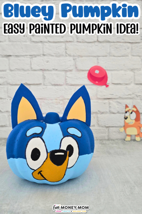 A pumpkin is painted to look like Bluey, the cartoon dog, with a paper backdrop showing a balloon and another character in the background. Text above reads, “Bluey Pumpkin Easy Painted Pumpkin Idea!”.