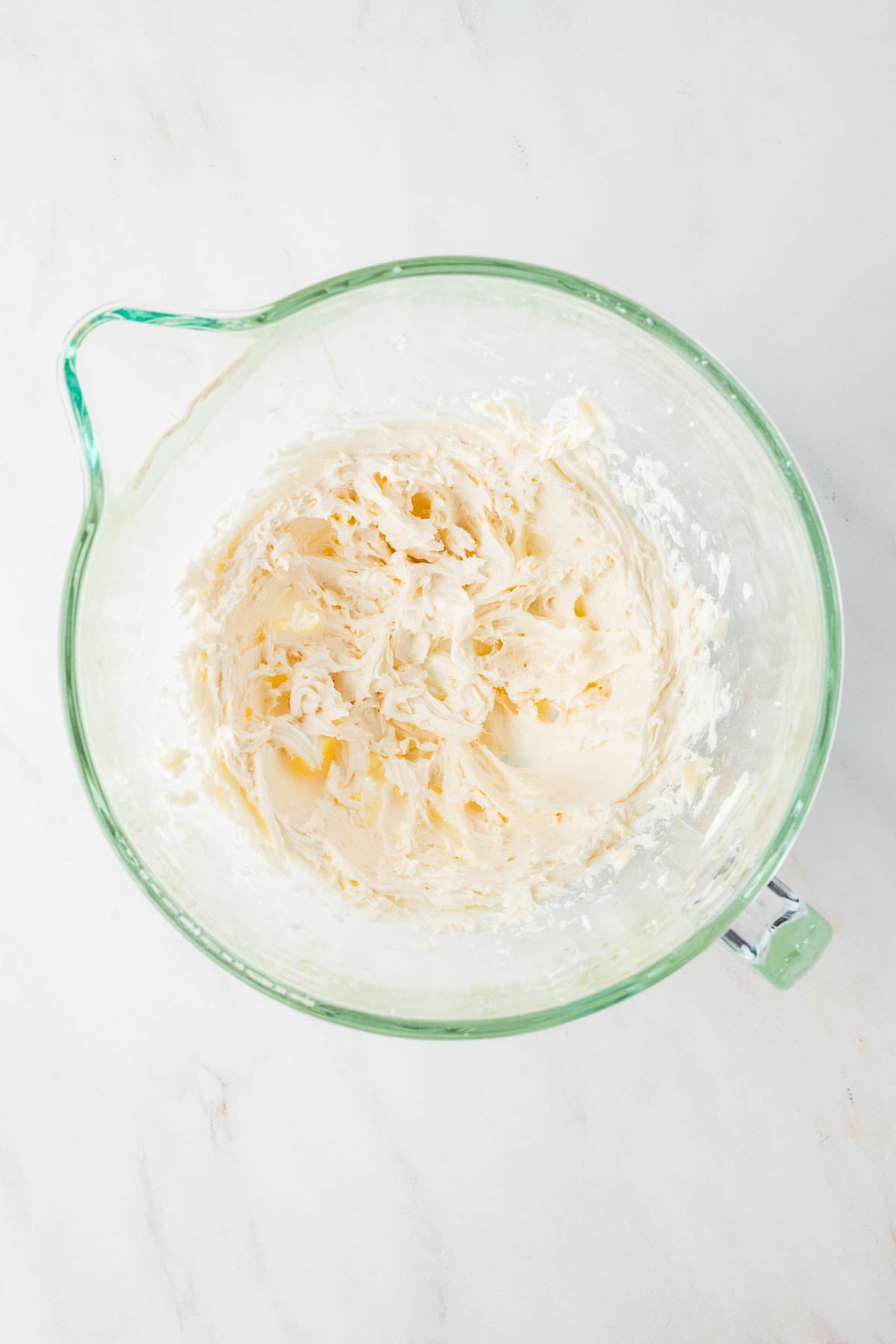 Creamy frosting in a glass mixing bowl.